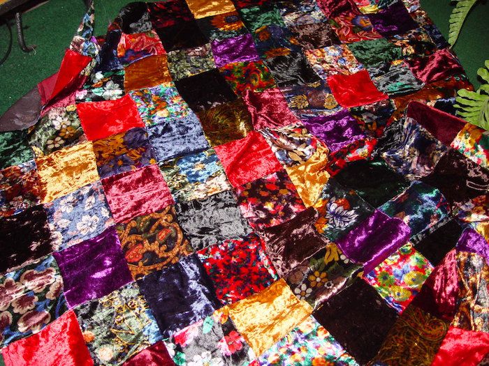 Quilt sy et fargerikt teppe med skinnende stoffer i lilla og rød farge