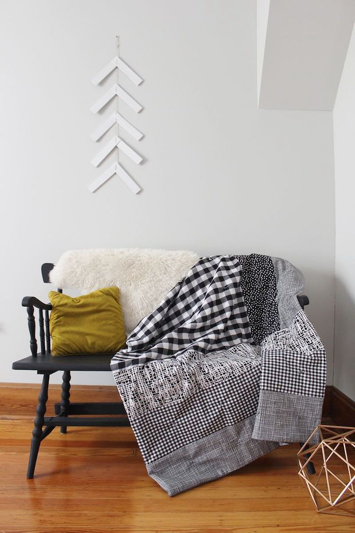 Quilt sy i grå farge laget av fire mønstrede stoffer plassert på en sofa