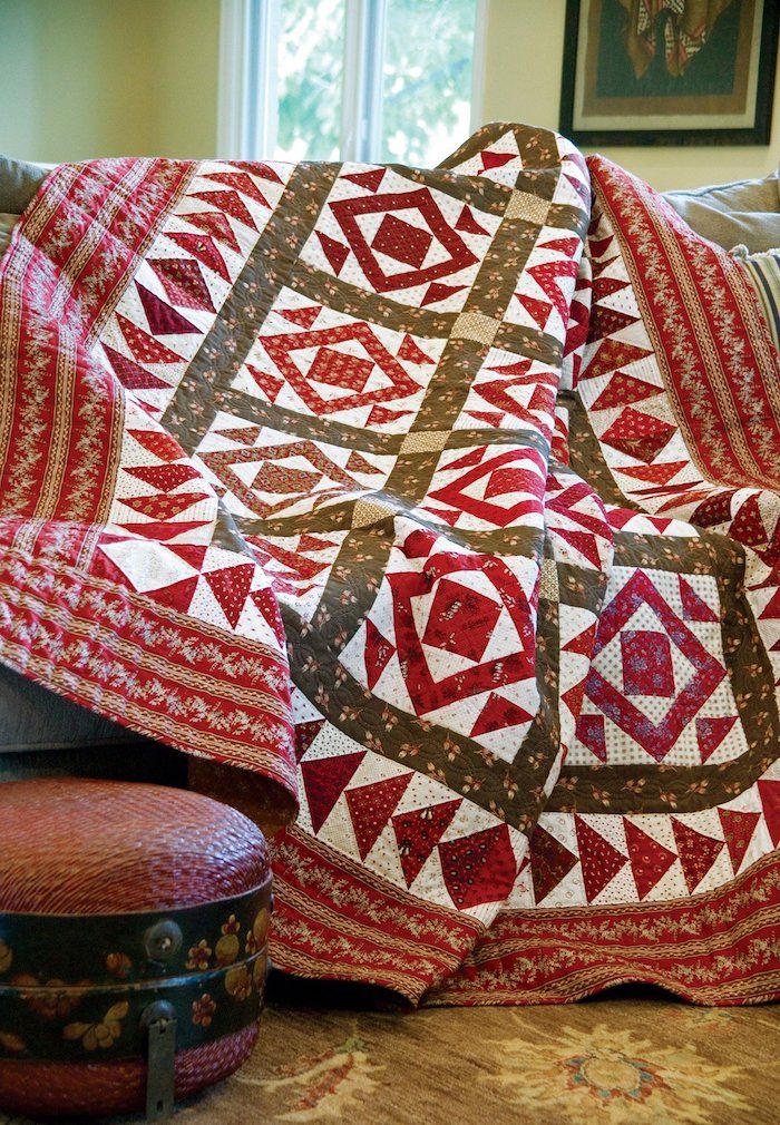 Quilt sy i farger grønn og rød med geometriske mønstre på sofaen
