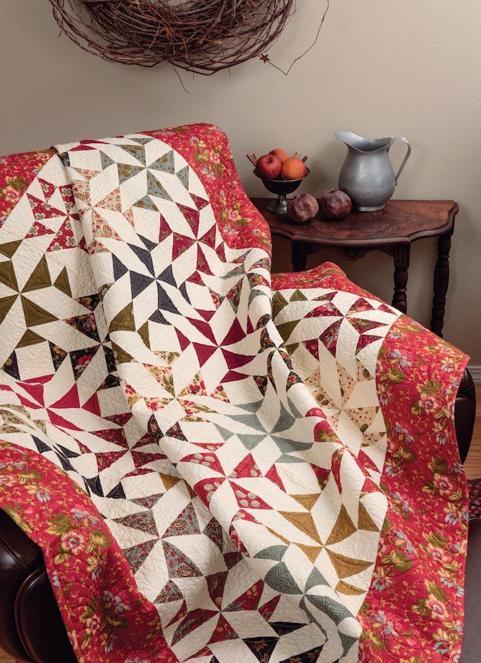 pătură roșie cu model floral pe margini și model geometric în pătură de mijloc