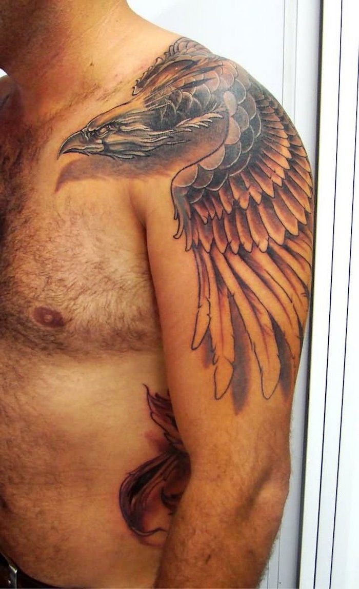 en man med en stor svart tatuering med en flygande Phoenix med vingar med långa svarta och vita fjädrar