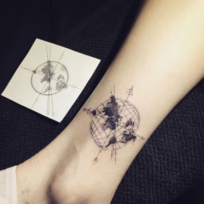 Tutaj przedstawiamy pomysł na tatuaż na nodze z czarnym kompasem z ziemią, planetami i czarnymi strzałami
