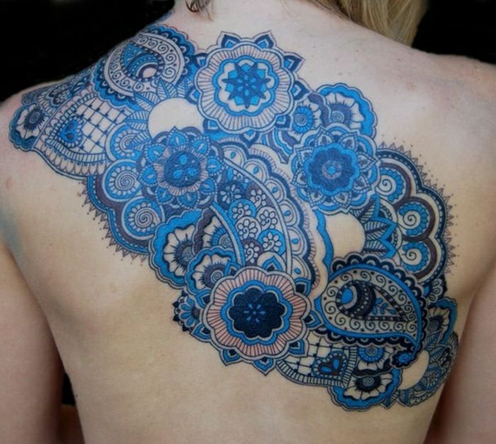 Vrouw met schouder en rug tattoo met kleine mandala's in vele nuances van blauwe, kleine ornamenten in donkere kleur