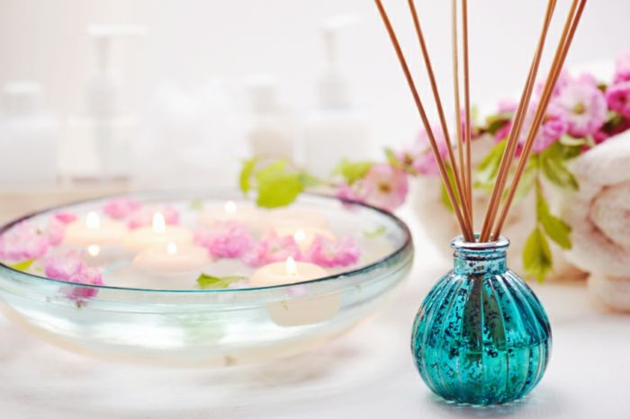 parfémová fľaša, vôňový difuzér, bambusové palice, plávajúce sviečky, voda, kvety