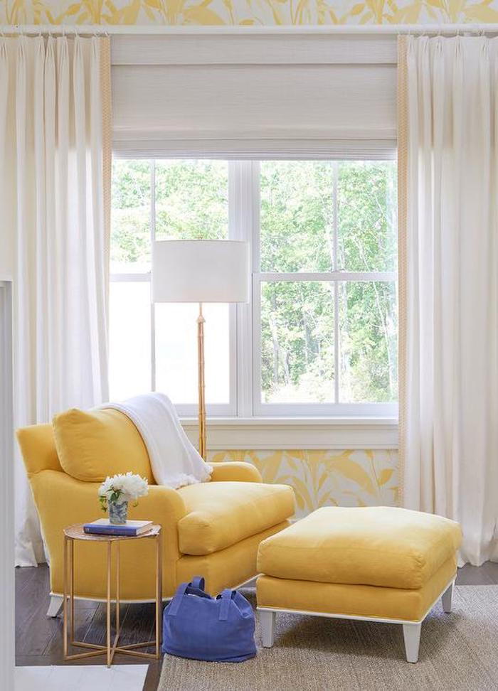 geltonai suprojektuota svetainė su nedideliu šoniniu stalu šalia poilsio kėdės su išmatomis