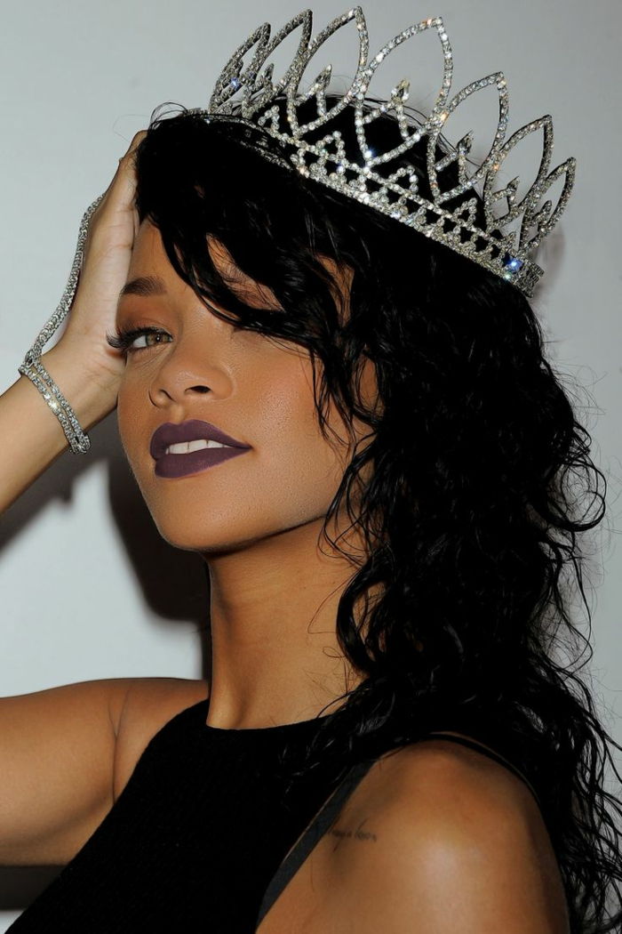 cabelo preto com cachos, uma grande coroa de prata, batom preto - penteado Rihanna