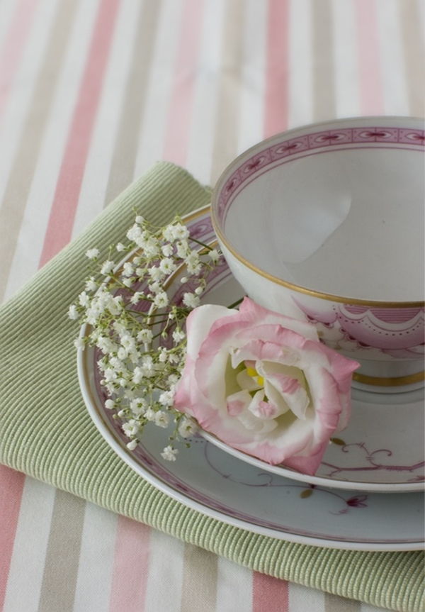 Papuoškite stalą su gražia rožine antklode ir porcelianine plokštele su baltomis gėlėmis