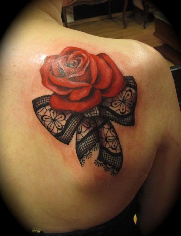 arco e una grande rosa rossa - idea per un tatuaggio rosso sulla spalla di una donna