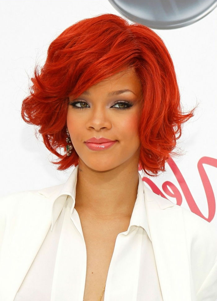 Rihanna su raudonaisiais plaukais, raudonaisiais plaukais ir tamsiu blizgesiu, rausvos lūpomis, baltu marškinėliai