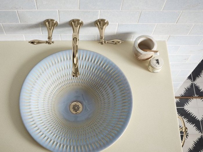 Enkelt badrum sink design i ljusblå och guldfärg, gyllene kran, ljusgul tvättbord