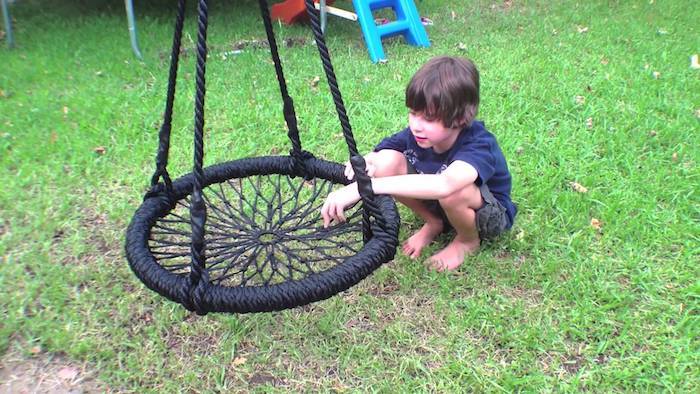 chlapec na lúke hrá s čiernym hojdačkou - detský hojdačka pre záhradu