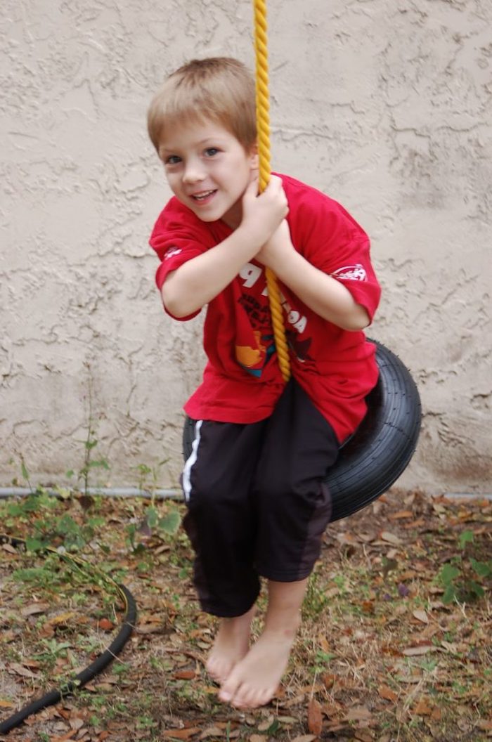 jednoduchý výkyv postavený z obručí a lana, chlapec s tréningovým oblekom