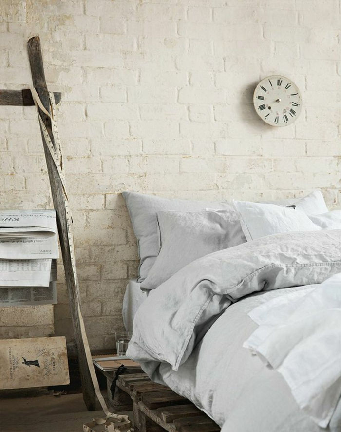 eenvoudige slaapkamer interieur euro pallets bed wit linnen wandklok-classic-model witte bakstenen muren
