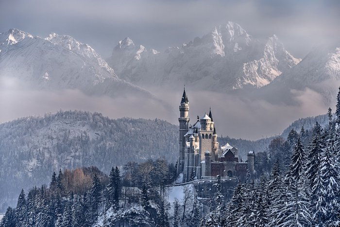 en skog med mange trær og snø - et slott med store tårn - vinterfjell med snø - himmel med hvite skyer