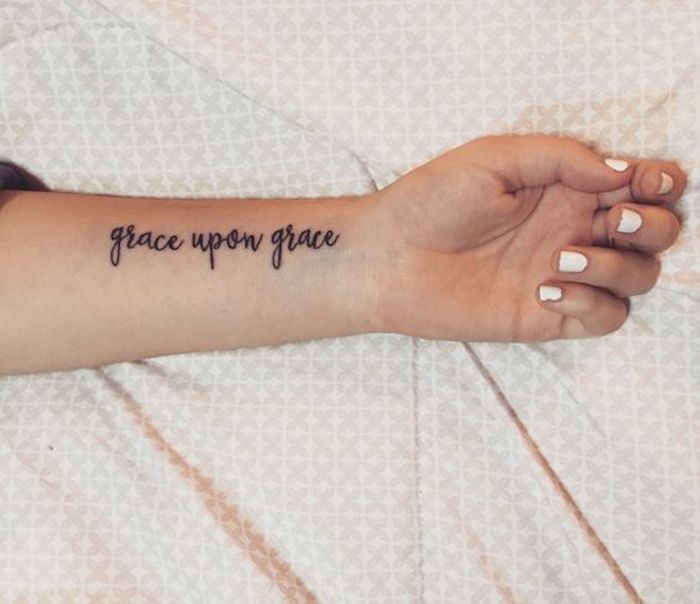 un citat religios la încheietura mâinii unei femei cu zugrăvire albă - tatuaj