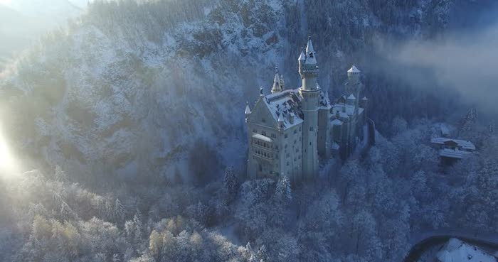 et slott med tårn i solnedgangen - en skog med mange trær med snø og hvite skyer