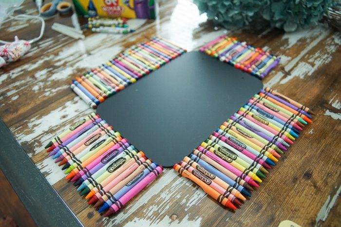 Dotări școlare drăguțe - creioane colorate, cum ar fi curcubeu, înconjoară o tablă neagră