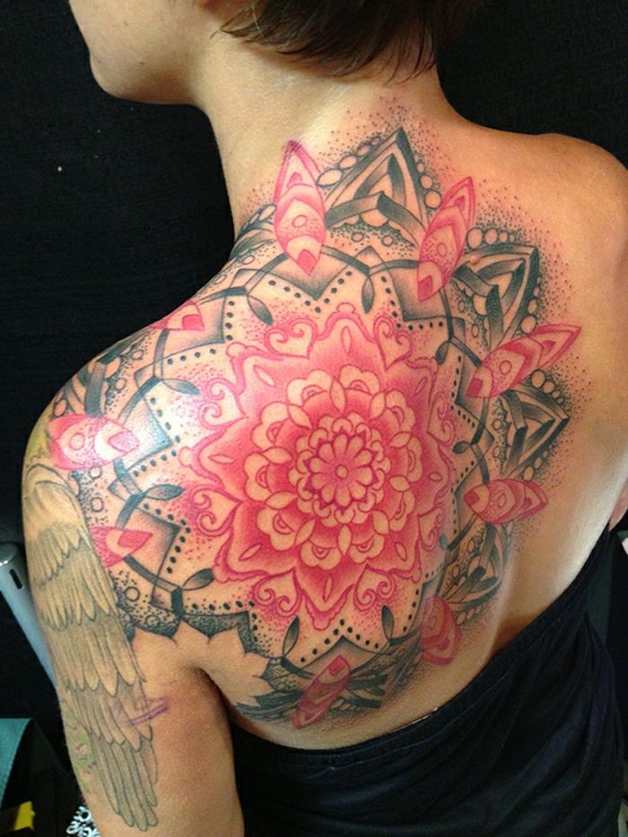 stor ornamental tatuering på vänster axel och vänster axelblad, topp till nacke och ner till baksidan, svart-röd tatuering med många svarta prickar och röda hjärtan, små hjärtmotiv, kvinna med kort frisyr och svart topp