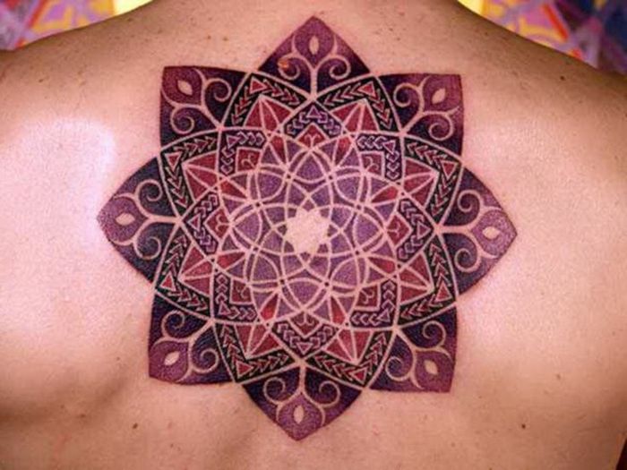 Späť tetovanie v strede chrbta v bordre, fialovej a fialovej, mandala bez kontúr s mnohými trojuholníkmi, späť s mnohými materskými znamienkami