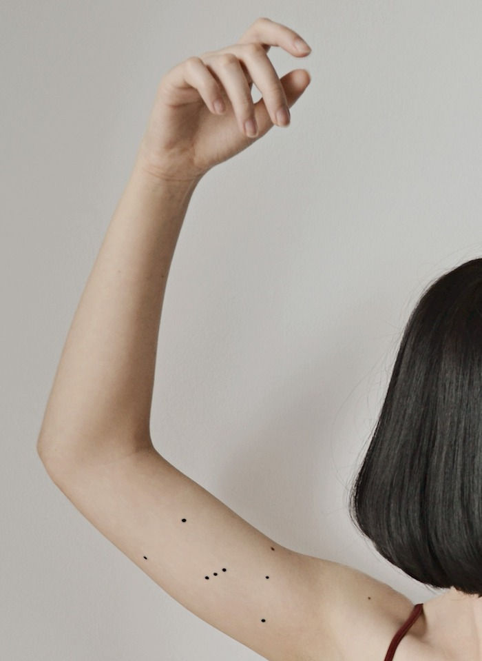 mlada ženska in tattoo z winzattoo s črno zvezdno podobo z majhnimi črnimi zvezdami - roko z zvezdicami tetovažo