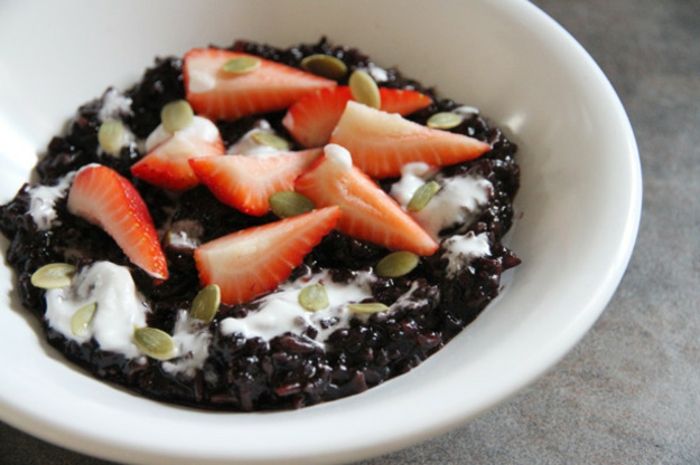 čierna ryža vyživujúca mliečnu ryžu zdobená jogurtom alebo zmrzlinou a tekvicovými semenami