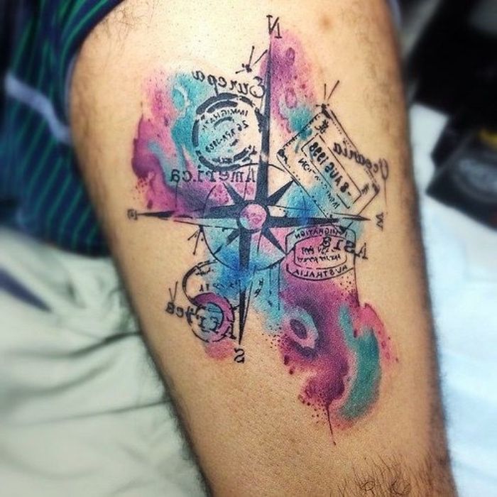 Velika tetovaža z velikim črnim kompasom s črnimi puščicami in žigi ter barvnimi barvami na roki