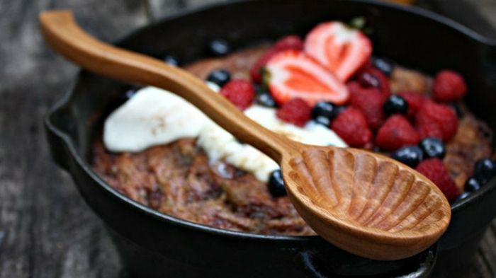 Nålverk, en svart keramisk krukke med kake og friske røde frukter, krem, treskje