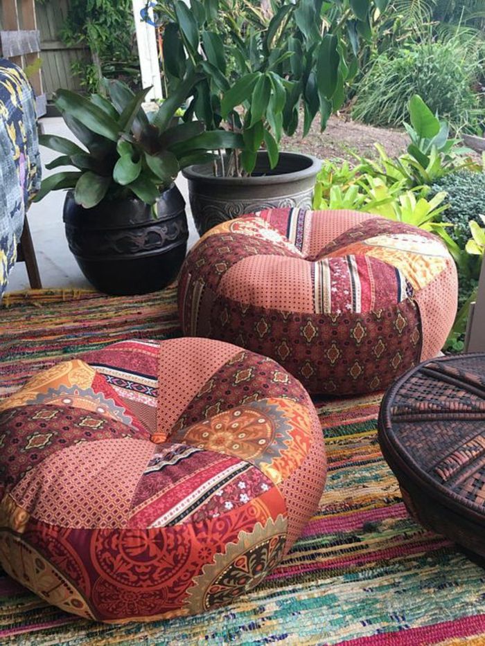 koselige puster i terrakottafarger, flerfarget teppe av hamp, dekorativt bord laget av tre, malt i mørkbrunt, lite hageområde med mange planter