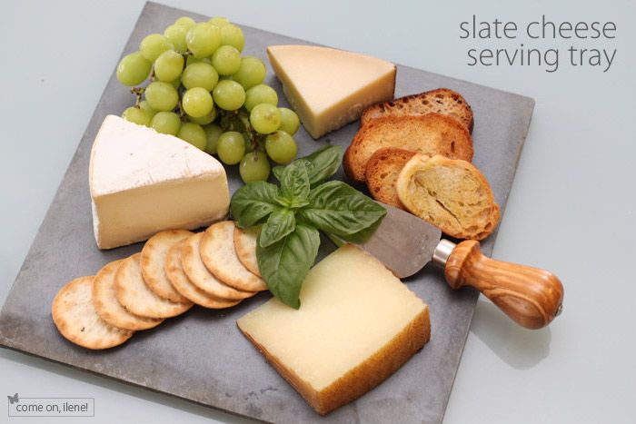 açık gri renkli lav taşı bir tabak resmi, yuvarlak meyveleri ile sulu çekirdeksiz üzüm, ahşap saplı peynir spatula