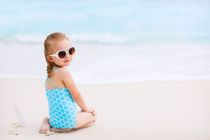 Meisje met fles zonnebrandcrème op tropisch strand