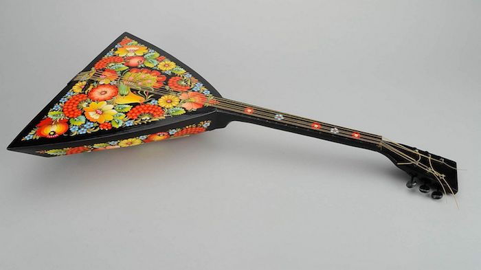 Balalaika - instrument de corzi în formă de triunghi cu corpus, decorat cu trei tipuri diferite de flori, mâner negru