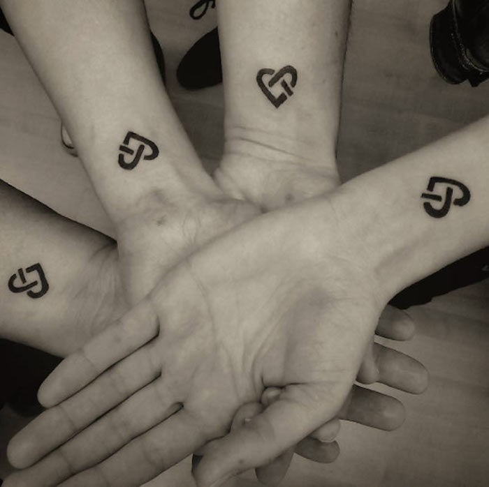 vier broers en zussen met een minimalistische hart-tatoeage op de pols - broer / zus-tatoeage