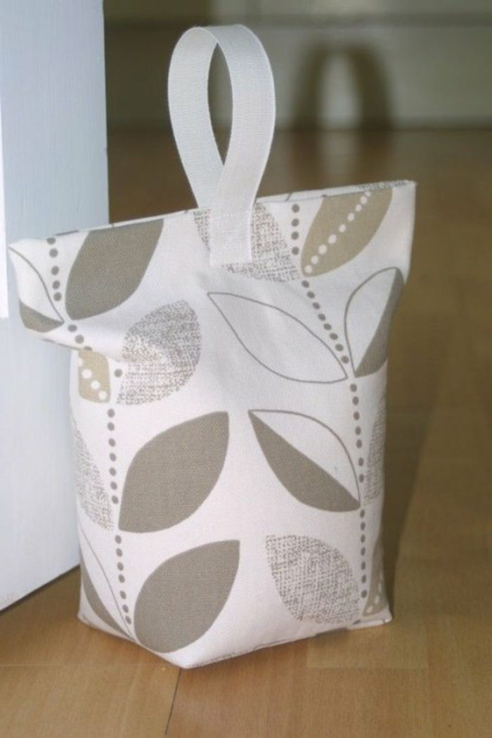 Fermaporta in colore bianco con foglie di colore grigio come una borsa