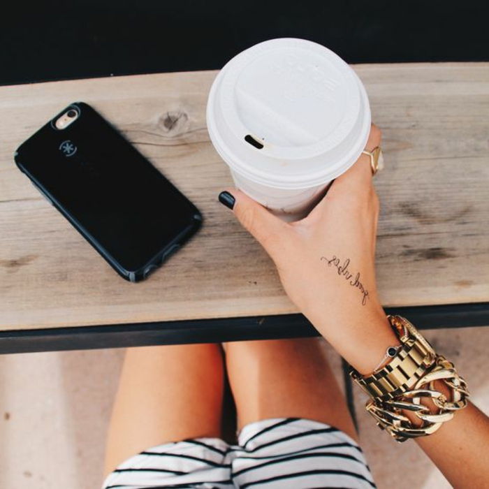 tatoveringsmotiver kvinne drikker kaffe armbånd armbåndsur tatovering mobiltelefon kort bukser rutet ring negle