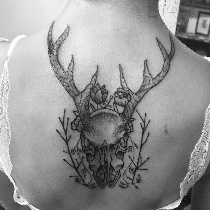 tetovaža lobanja - ženska s črno tetovažo z lobanjo jelena z velikimi rogovi in ​​dvema majhnima cvetjema