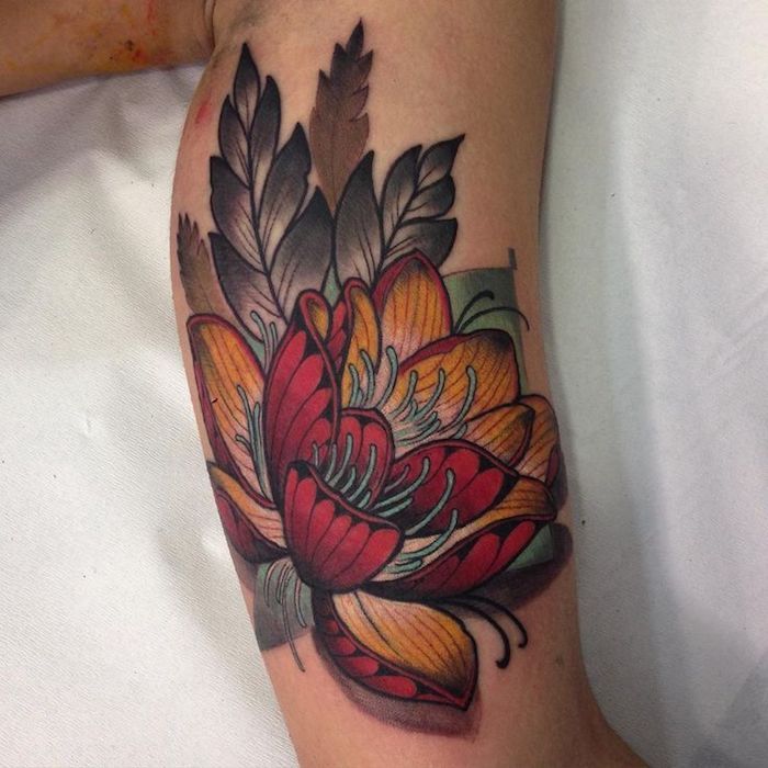 kwiat tatuażu, kwiat lotosu w kolorze czerwonym i pomarańczowym na ramieniu, tatuaż na ramię