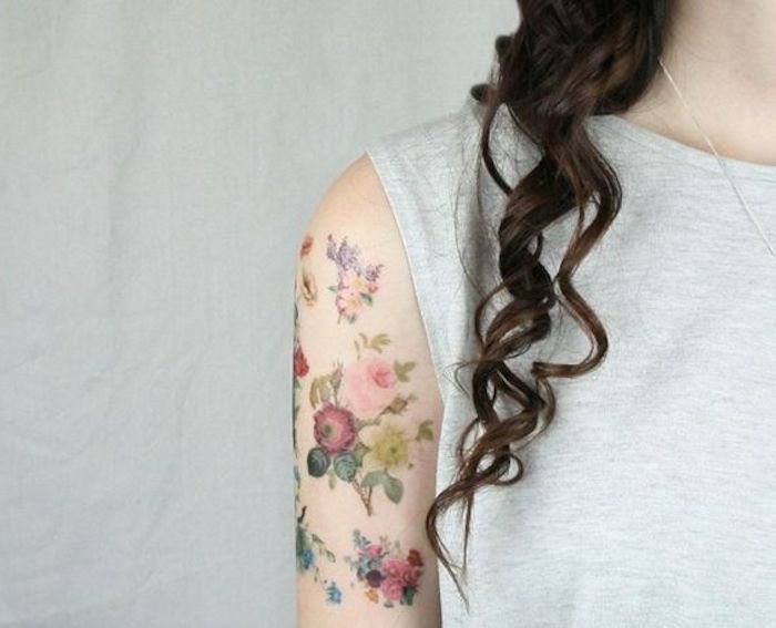małe kwiaty, kolorowy tatuaż, tatuaż na ramię, kobieta z kręconymi włosami