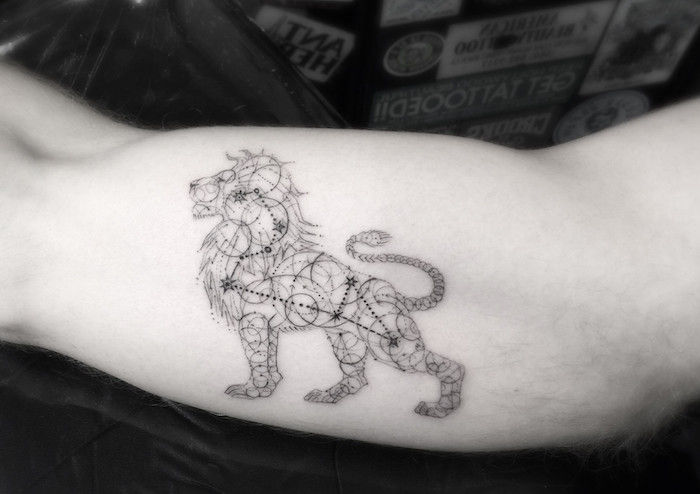 Een tatoeage met een zwarte leeuw en een zwart sterrenbeeld met kleine zwarte sterren
