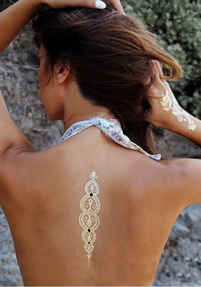 tatoveringer kvinne gyldne farger tatoveringer på baksiden og hånddekorasjon for kroppen nakkekjæringsstrand