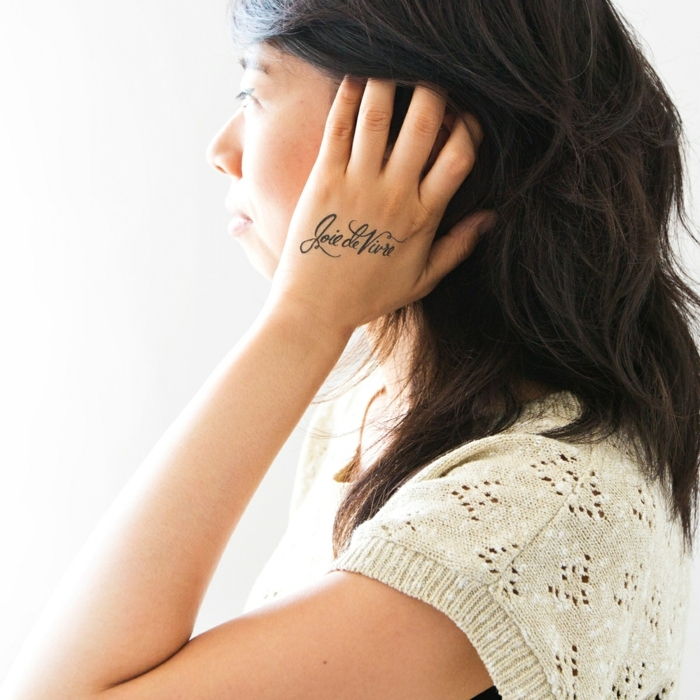 Motivi del tatuaggio idea sottile per le donne che scrivono sulla mano camicetta in maglia di pizzo nero