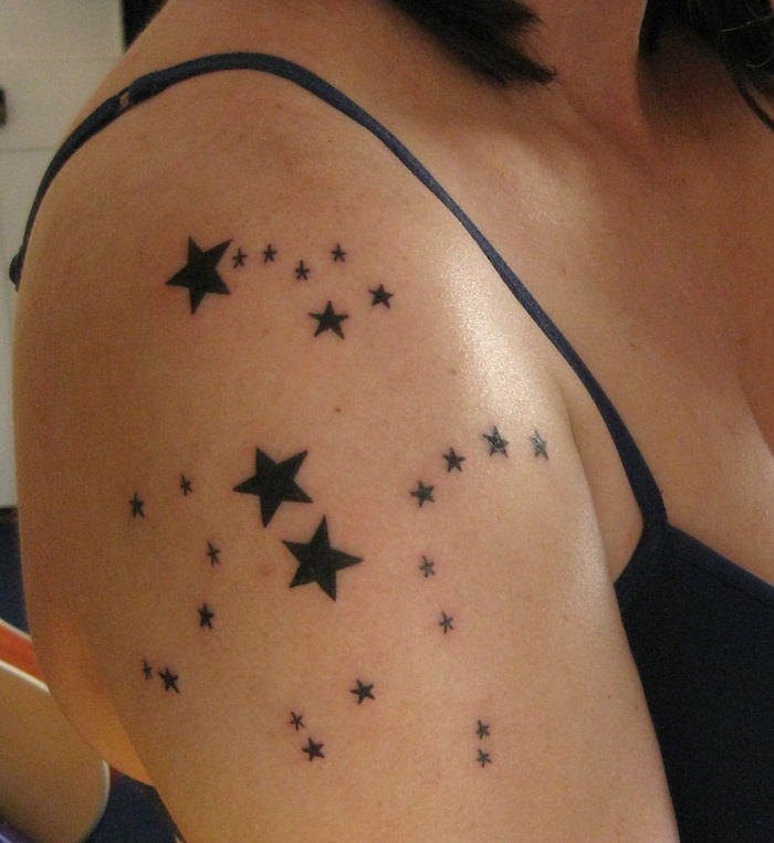 tetovanie rameno - žena s čiernym tetovaním s mnohými malými a veľkými čiernymi hviezdami