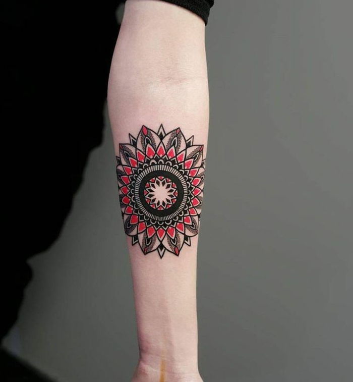 Mandala aan de binnenkant op de onderarm, mandala in zwart en rood, lange zwarte jurk met korte mouwen