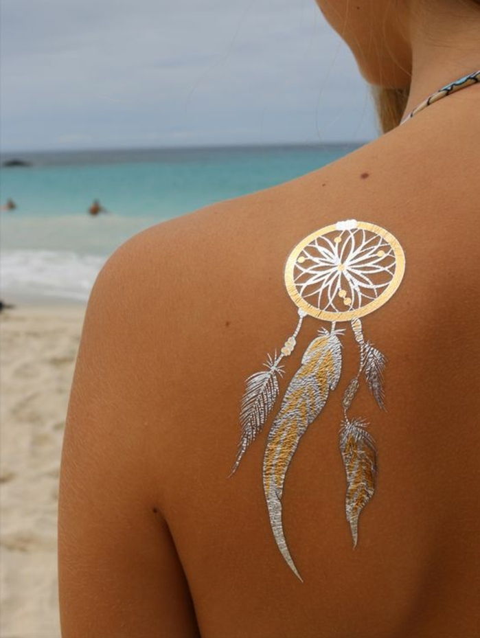 tatuaggio spalla donna dreamcatcher idee in argento e oro mare mare ambiente grigio con costume da bagno