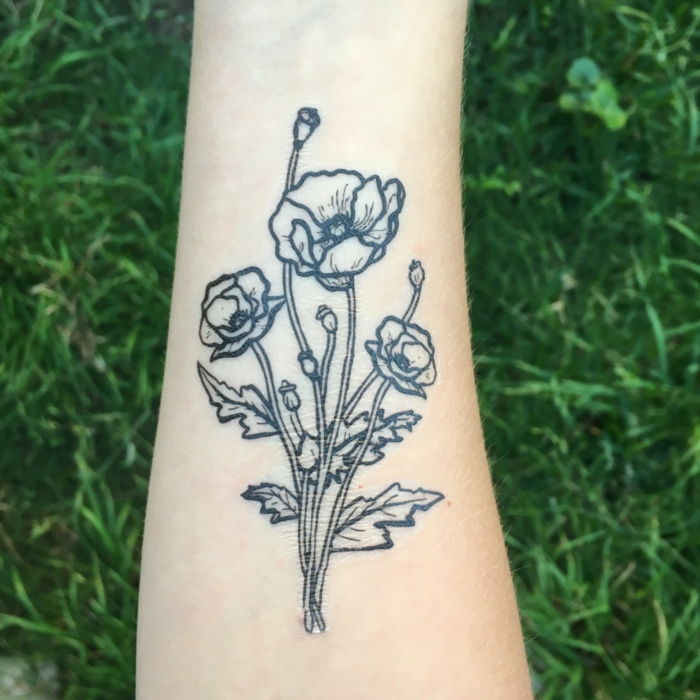 i papaveri sul braccio decorano il tatuaggio temporaneo stesso rendono l'idea della natura dell'erba verde