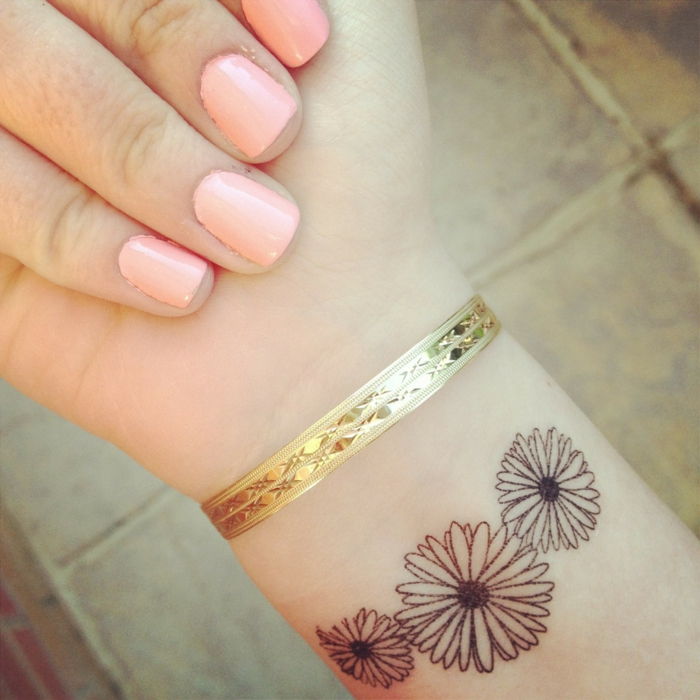 subtile tatovering utformet i form av tre vakre små blomster gylne armbånd flott manikyr