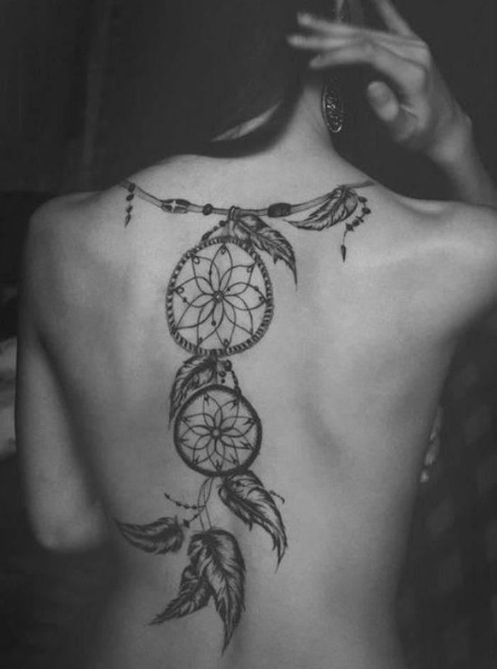 Dream catcher tattoo på baksidan av en kvinna med stora örhängen