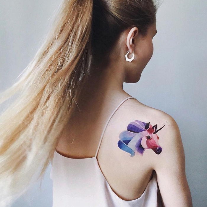 en enhjørning tatovering på skulderen i lilla, rød og blå farget akvarell tatovering