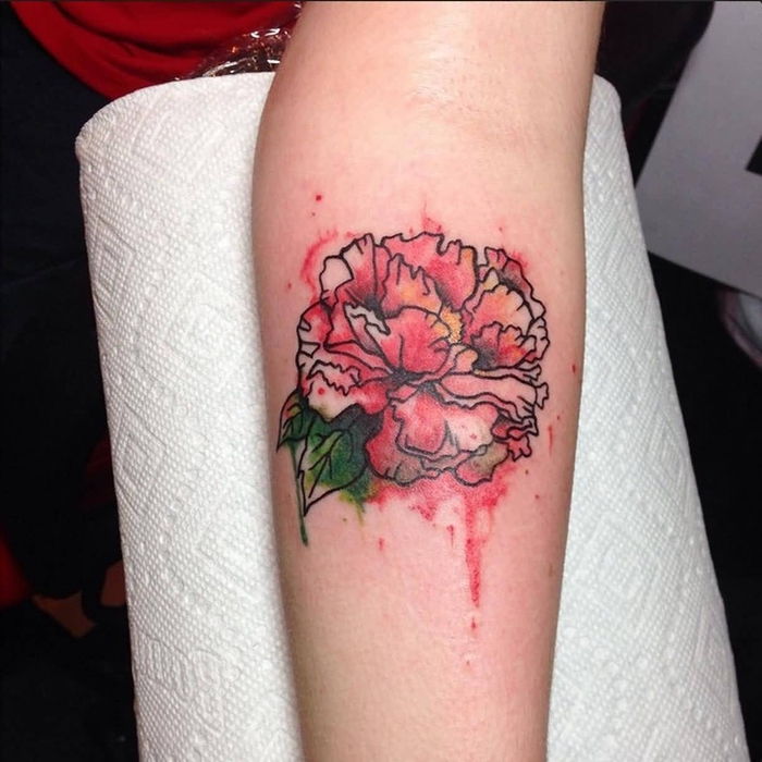 Akvarell tatovering en rød blomst og hennes grønne blader på armen ganske kunstig