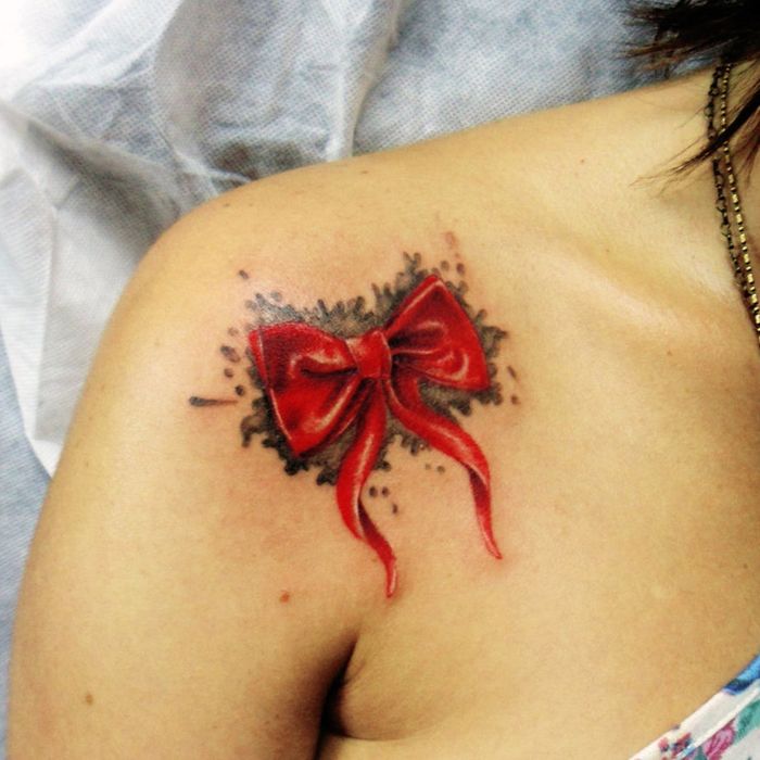 rött band på svart bakgrund på tatueringen på axelvattenfärgen