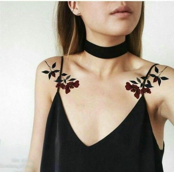 Două tatuaje de femeie pe cele două umerii unei flori de cercei de sus negru a unei femei